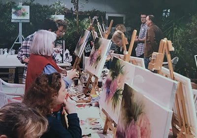 A group of people painting flowers on canvas.