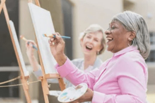 Two women are painting on a canvas.