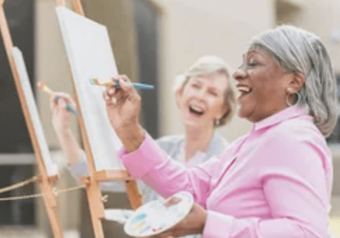 Two women are painting on a canvas.